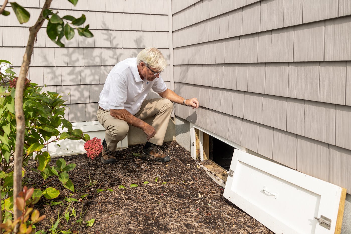 Home inspector examining a crawl space access area